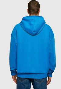 Blue hoodie with a large hood, loose fit, and ribbed cuffs. Made from soft fabric, featuring a smooth texture and solid color design.