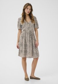 Robe en imprimé léopard avec de courtes manches bouffantes, taille cintrée et jupe évasée. Tissu doux dans des tons beiges et marron avec une texture subtile.