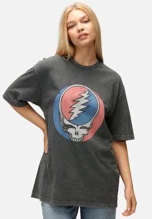 Camiseta gris de gran tamaño con un gráfico audaz de una calavera dentro de círculos rojos y azules. Material de algodón con una sutil textura desgastada.