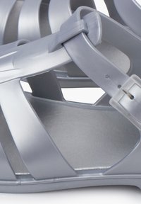 Gray plastic sandals with open-toe design, featuring crisscross straps and adjustable buckles. Smooth interior texture and durable exterior.