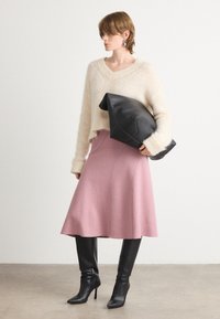 Pulover scurt, texturat, de culoare bej deschis, cu mâneci lungi, asortat cu o fustă din lână roz, tip cloș. Botine negre cu toc înalt până la genunchi și o geantă neagră de mână.