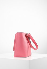 Różowa skórzana torebka o zdefiniowanej formie, smukłych uchwytach i prostych liniach. Charakteryzuje się gładką fakturą i subtelnymi kontrastowymi przeszyciami.