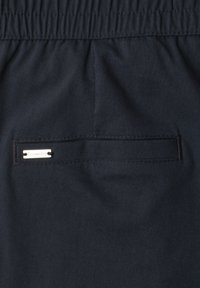 Close-up of dark fabric pants with an elastic waistband and a horizontal back pocket featuring a small "Street One" metal label.