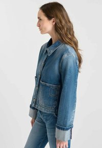 Blå denimjacka med knappfäste fram, spetsig krage och två framfickor. Har kontrasterande denimmanchetter och broderad detalj.