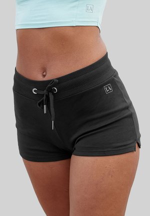 Black athletic shorts with a ribbed waistband, drawstring closure, and side slits. Soft fabric with a fitted design, logo tag on waistband.