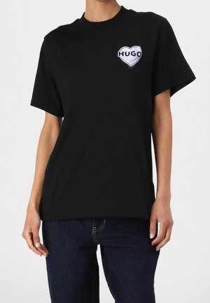 T-shirt en coton noir avec un logo en forme de cœur portant "HUGO" en blanc, à manches courtes et à coupe décontractée.