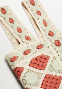 Sac fourre-tout crocheté crème et rouille avec des motifs géométriques carrés et ovales, présentant des points texturés et des détails en ajouré.