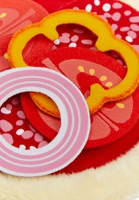 Colorful felt food play pieces, including red slices, a yellow ring, and a pink striped circle, featuring textured surfaces and various patterns.