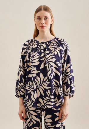 Marinebluse mit beigem Blattmuster, rundem Halsausschnitt, gerafften elastischen Ärmeln und lockerer Passform, kombiniert mit passenden Hosen.