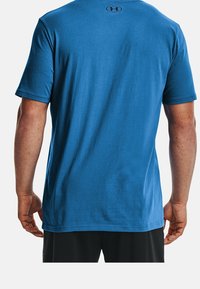Blue short-sleeve t-shirt made of cotton, featuring a smooth texture and a logo at the upper back. T-shirt has a relaxed fit.