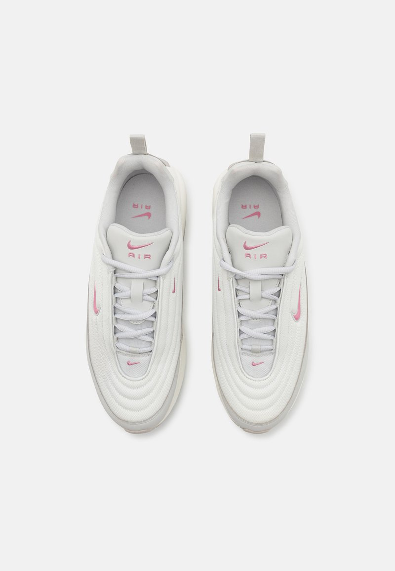 Scarpe sportive bianche con logo Nike rosa, tomaia textured, forma arrotondata, chiusura con lacci e un'etichetta sul retro per una facile indossabilità.