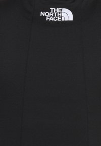 Black short-sleeve sweatshirt featuring a white logo of The North Face on the left chest area, made of soft, textured fabric.