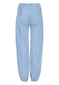 Šviesiai mėlynos spalvos tamprios juosmens džinsinės kelnės su raukšlėtu raštais klubų srityje ir elastinėmis apačiomis kulkšnies srityje, galinis vaizdas.