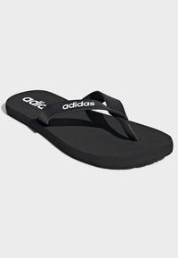 Chanclas negras con suela texturizada y tira suave, con el logo blanco de "adidas". Diseño sencillo, material ligero y forma plana.