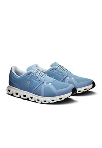 Baskets de sport bleu clair avec tige en maille respirante, semelle blanche et capuchon de orteil noir contrastant. Présente des lacets et des accents de marque subtils.