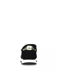 Sneaker in suede nero con suola intermedia bianca. Presenta una forma arrotondata e un dettaglio metallico sul tacco, impresso con il nome del marchio "SUN68."