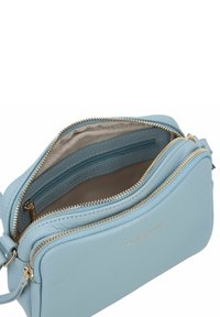 Borsa a tracolla in pelle blu chiaro con zip dorate, dotata di un ampio interno e vari scomparti per un'organizzazione ottimale.