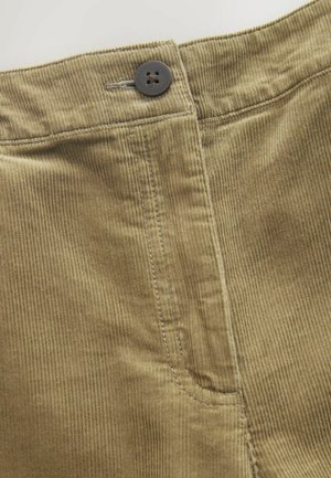 Brauner Cordstoff mit vertikaler Rippstruktur, sichtbarer Tasche und Knopfverschluss an der Taille. Detaillierte Nähte setzen Akzente.