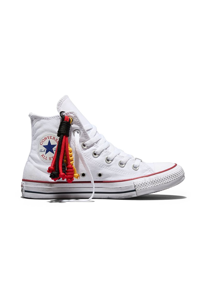 White high-top Converse sneaker with red and black cord tassel attached near metal eyelets on the side.