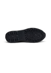 Sole di scarpa nera con profili profondi in modelli geometrici, tra cui triangoli e diamanti, su uno sfondo bianco semplice.