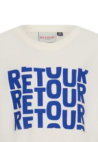 Witte katoenen T-shirt met een groot, vet, blauw grafisch tekstontwerp van "RETOUR" in verschillende oriëntaties. Ribbelboord kraag.