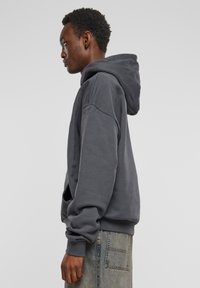 Grijze oversized hoodie met een voorste zak en een capuchon met trekkoord. Gemaakt van zachte stof, met verlaagde schouders en geribbelde manchetten.