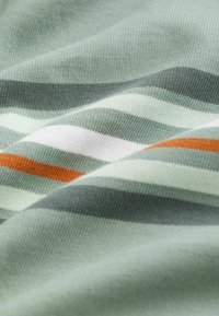 Bavlněná látka s horizontálními pruhy v světle zelené, šedé, bílé a oranžové barvě. Měkká textura s hladkým pleteným povrchem.