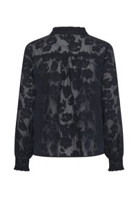 Blouse noire transparente à manches longues avec motif floral texturé, empiècement froncé au dos et poignets élastiqués smockés.