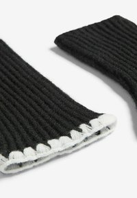 Mănuși negre tricotate fără degete, cu o textură răsucită, având un detaliu cu margine zimțată albă pe încheietura mâinii.