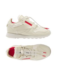 Baskets en cuir blanc avec des accents rouges, tige texturée, lacets plats, boîte à orteils perforée et semelle épaisse en caoutchouc.