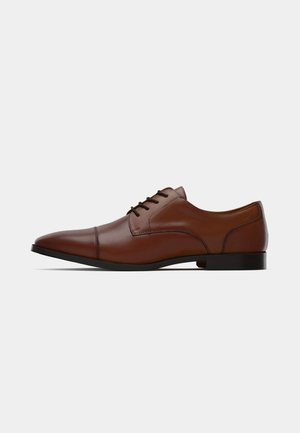 Chaussure habillée en cuir marron avec un embout pointu, texture lisse, design à lacets et une semelle noire basse. Présente des coutures discrètes le long du dessus.