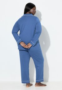 Blaues langärmliges Pyjama-Set aus weichem Stoff, mit weißen Paspeln an Ärmeln und Hosen, lockere Passform und gerade geschnittene Beine.