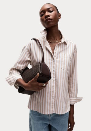 Striped beige and white button-up shirt with a front pocket, paired with a dark brown woven handbag and blue jeans. Textured fabric and casual fit.