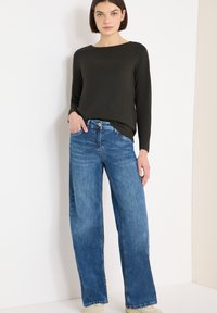 Black long-sleeve top with a round neckline, paired with light blue wide-leg jeans made of denim. The outfit has a relaxed fit and casual style.