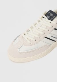 Ανοιχτόχρωμο sneaker που συνδυάζει suede και συνθετικό δέρμα, με αντίθετες ναυτικές ρίγες και υφασμένο καουτσούκ σόλα.
