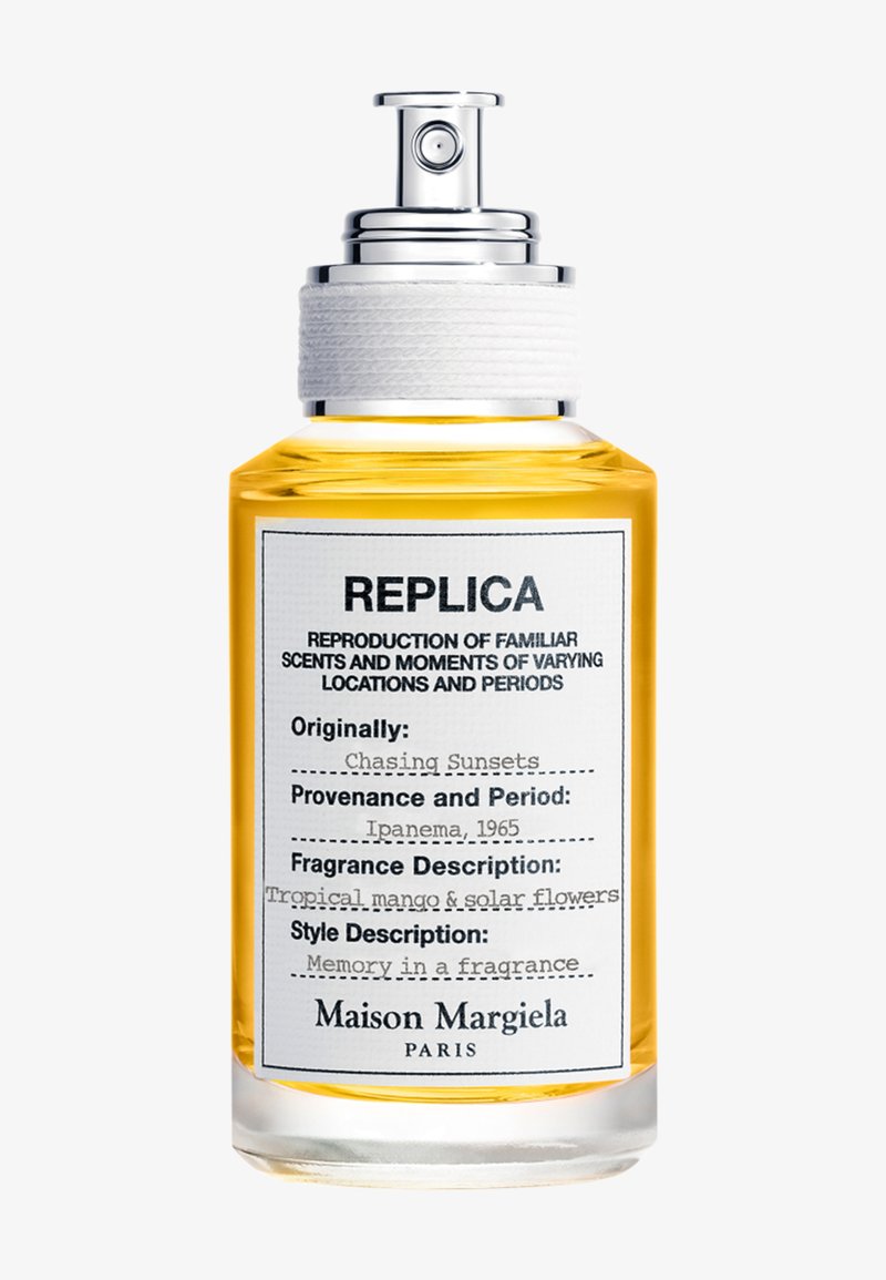 Bouteille de parfum en verre transparent avec pulvérisateur argenté, remplie d'un liquide ambré, étiquetée "Replica Chasing Sunsets" par Maison Margiela, Paris.