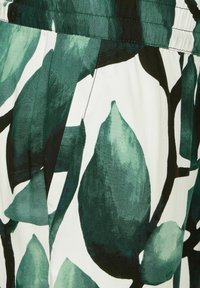 Grön- och svartbladigt mönster på vitt tyg, med elastisk midja och en söm för sidoficka.