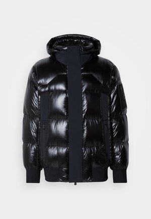 Giacca a vento nera con finitura lucida, cappuccio, chiusura con zip e polsini a coste. Include due tasche laterali e una patch con logo sulla manica.