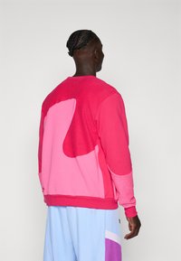 Kleurrijke sweatshirt met grote abstracte vormen in roze en lichtroze, met een gestructureerde stof, ronde halslijn en ribgebreide manchetten.