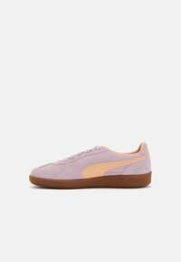 Sneaker in suede viola chiaro con accenti arancioni, suola in gomma marrone, punta arrotondata e design con lacci. Il lato presenta un logo distintivo.