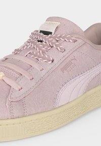 Ανοιχτό ροζ σουέτ αθλητικό παπούτσι Puma με υφή μπεζ σόλας, πλεκτά κορδόνια και λογότυπο Puma στο πλάι και στη γλώσσα.