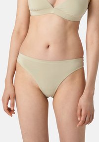Bikini de parte inferior de mezcla de algodón color beige claro con diseño de tiro bajo, textura suave y costuras mínimas a lo largo de la cinturilla y los bordes de las piernas.