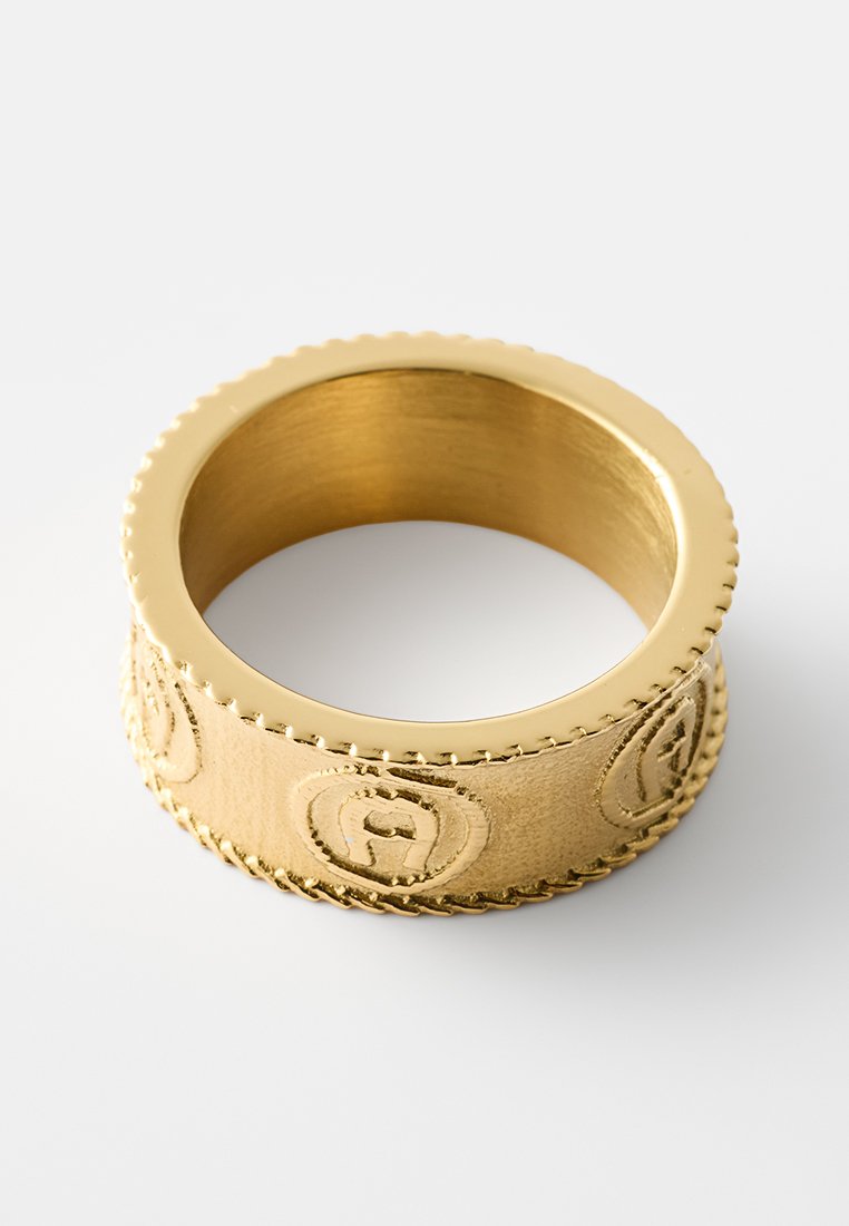 Goldfarbener Ring mit strukturiertem Oberflächenfinish, versehen mit eingeprägten Logos rund um den Ring und einem glatten Innenbereich, der eine dicke, abgerundete Form präsentiert.