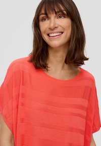 Koraal oversized brei top met horizontaal streeppatroon, brede halslijn en korte mouwen. Zachte textuur en lichtgewicht stof.