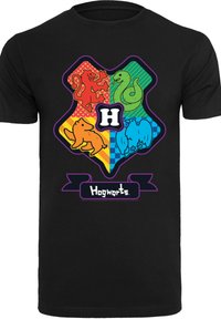 Svart t-skjorte med et fargerikt emblem som viser fire husdyr: en løve, slange, bjørn og fugl, sammen med teksten "Hogwarts" under.