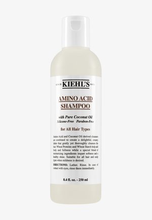 Botella de plástico transparente con una tapa blanca de tipo flip-top, etiquetada "Champú de Aminoácidos de Kiehl's", con texto en negro. Contiene 250 ml.