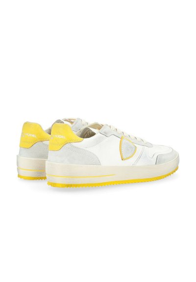 Sneakers in pelle bianca con dettagli in suede grigio e suola in gomma gialla. Presentano un emblema giallo e un design testurizzato sui lati.