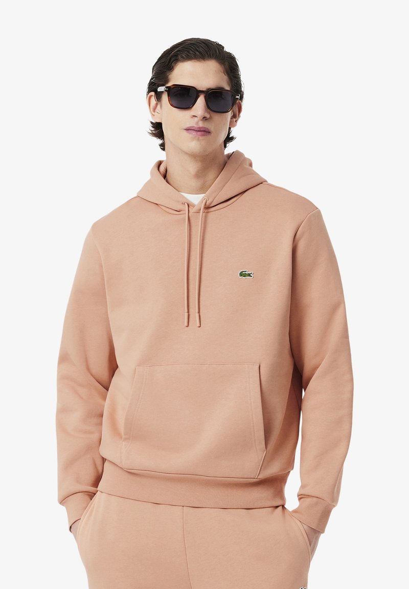 Felpa con cappuccio pesca in morbido misto cotone, con tasca frontale, polsini e orlo a coste, presenta un piccolo logo verde sul petto.