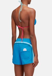 Blauw bikini top met halternek en roze strikken, gecombineerd met blauwe shorts met witte en groene strepen en een achterzak.