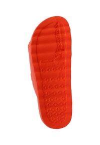 Red rubber shoe sole with textured surface. Features circular and rectangular patterns for grip. Curved shape extending to sides.